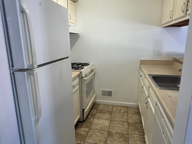 kitchen with white appliances, sink, and white cabinets