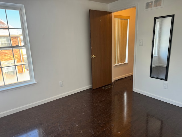 spare room with dark hardwood / wood-style floors and a healthy amount of sunlight