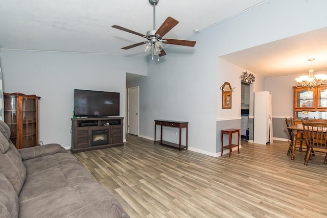 living room featuring hardwood / wood-style flooring, ceiling fan with notable chandelier, and vaulted ceiling