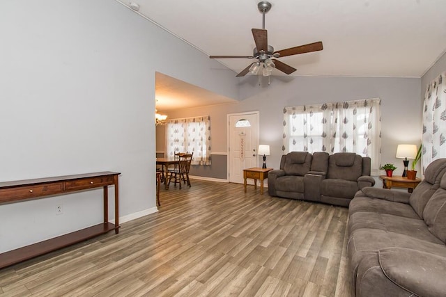 living room featuring lofted ceiling, hardwood / wood-style floors, ceiling fan with notable chandelier, and plenty of natural light