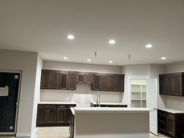 kitchen featuring a kitchen island with sink, light countertops, a sink, and recessed lighting