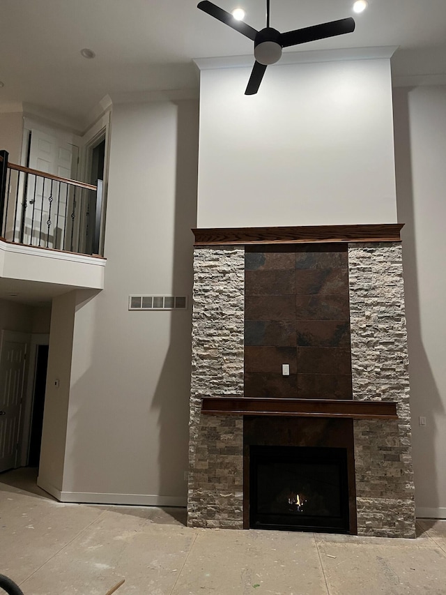 unfurnished living room featuring a ceiling fan, a warm lit fireplace, visible vents, and baseboards