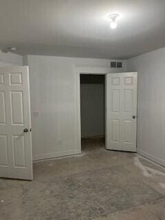 unfurnished bedroom with baseboards, visible vents, concrete flooring, and a closet