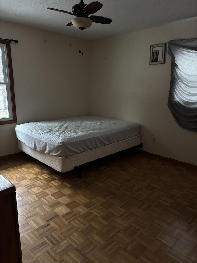 unfurnished bedroom featuring dark parquet flooring and ceiling fan