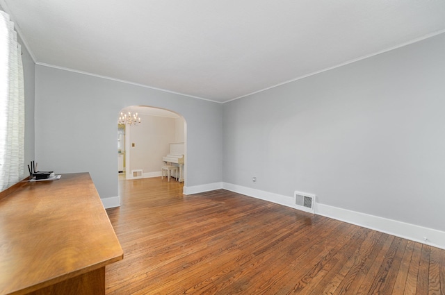 spare room with crown molding, hardwood / wood-style flooring, and an inviting chandelier