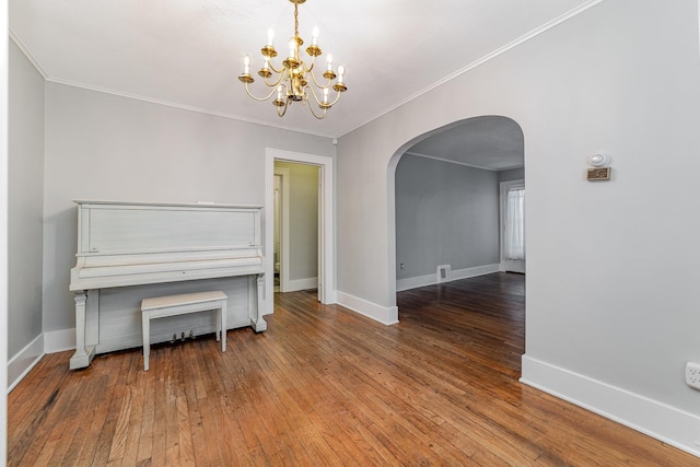 misc room with an inviting chandelier, ornamental molding, and wood-type flooring