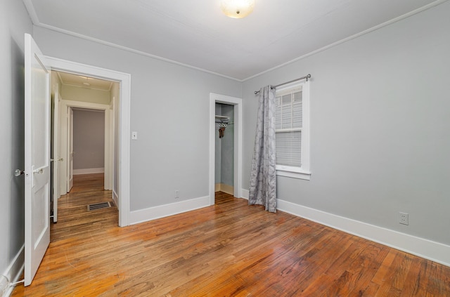 unfurnished bedroom with crown molding, light hardwood / wood-style floors, and a closet