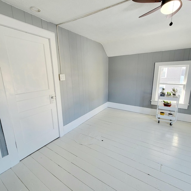 interior space with ceiling fan, vaulted ceiling, a textured ceiling, and light hardwood / wood-style floors