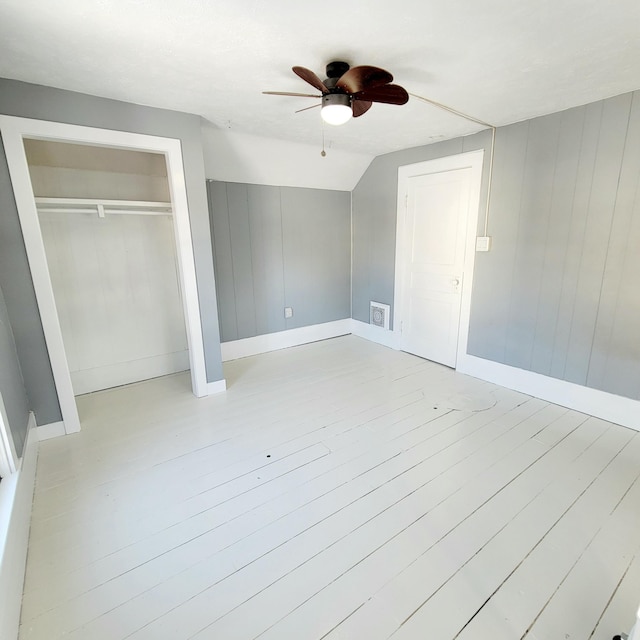 unfurnished bedroom with lofted ceiling, a closet, ceiling fan, and light wood-type flooring