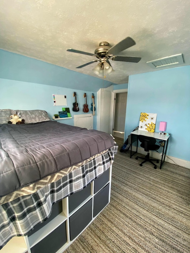 bedroom with ceiling fan, carpet floors, and a textured ceiling