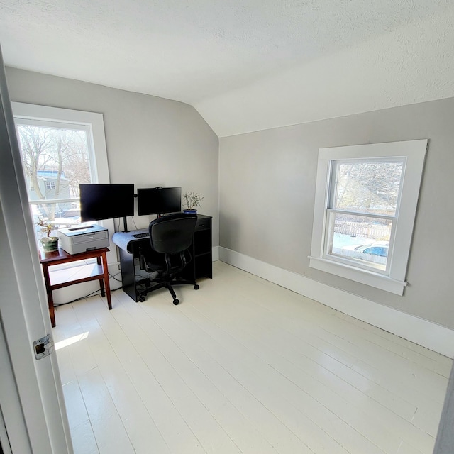 home office featuring lofted ceiling, a textured ceiling, and light wood-type flooring