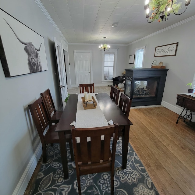 dining room featuring an inviting chandelier, a multi sided fireplace, ornamental molding, and hardwood / wood-style flooring