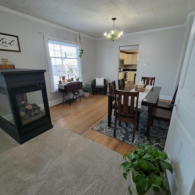 dining room featuring crown molding, hardwood / wood-style floors, a multi sided fireplace, and a chandelier