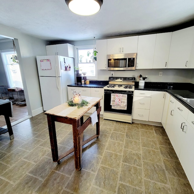 kitchen featuring white refrigerator, gas stove, and white cabinets