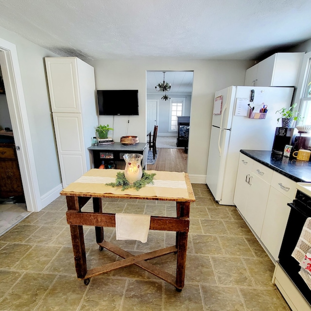 kitchen featuring stove, white cabinets, and a textured ceiling