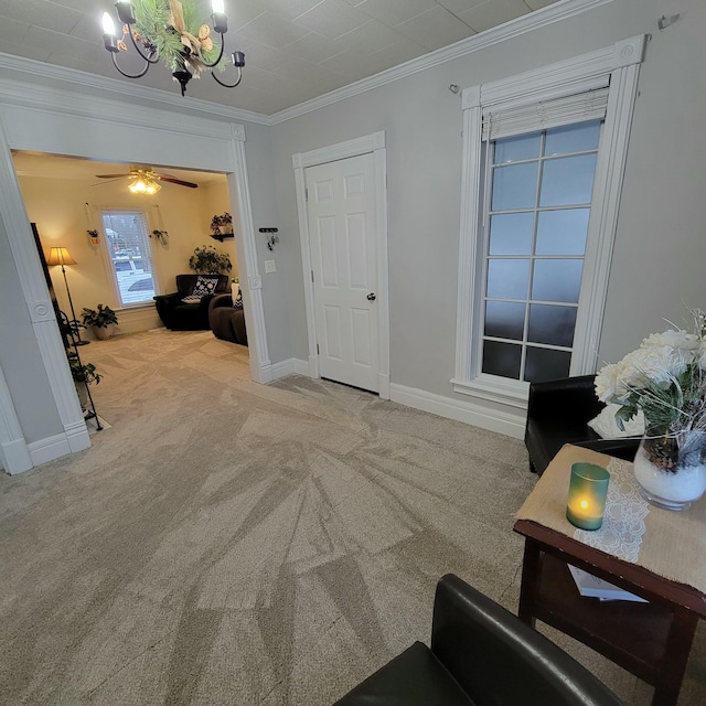 carpeted foyer entrance featuring ornamental molding and ceiling fan with notable chandelier