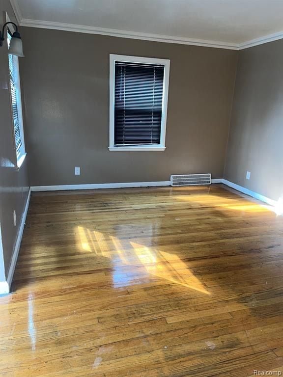 unfurnished room with hardwood / wood-style flooring and ornamental molding