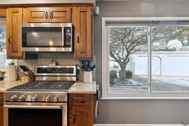 kitchen with stainless steel appliances, tasteful backsplash, and light stone counters