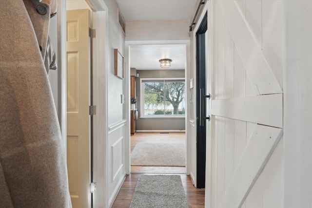 corridor with wood-type flooring and a barn door