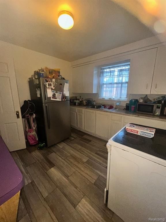 kitchen with appliances with stainless steel finishes, dark hardwood / wood-style floors, and white cabinets