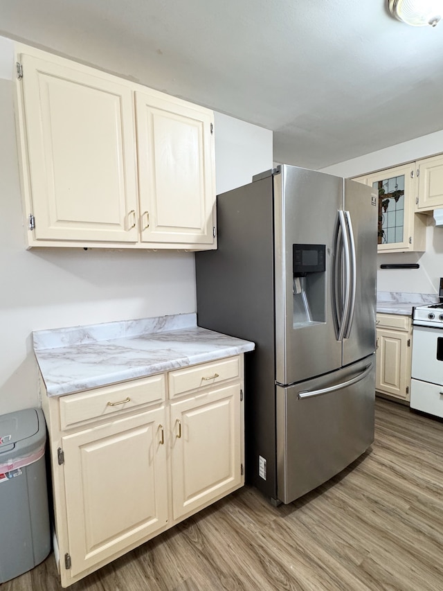 kitchen featuring hardwood / wood-style floors, white range with gas stovetop, and stainless steel fridge with ice dispenser