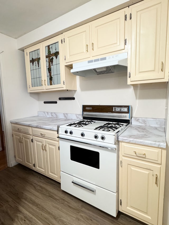 kitchen with dark hardwood / wood-style flooring, white range with gas stovetop, and cream cabinetry