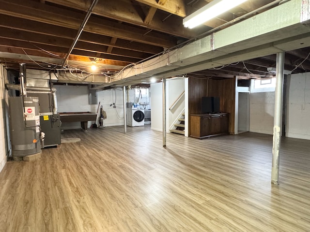 basement with hardwood / wood-style flooring, independent washer and dryer, water heater, and heating unit