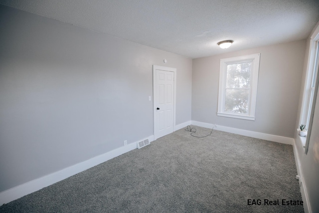 carpeted spare room with a textured ceiling