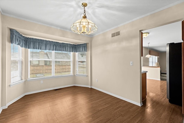 unfurnished dining area with crown molding, dark hardwood / wood-style floors, and a chandelier