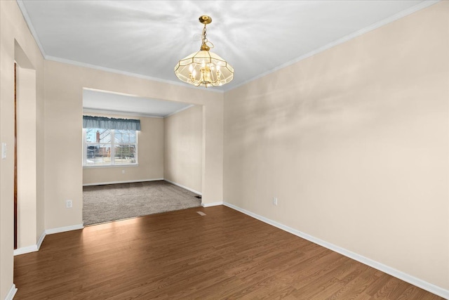 spare room with dark wood-type flooring, ornamental molding, and a notable chandelier