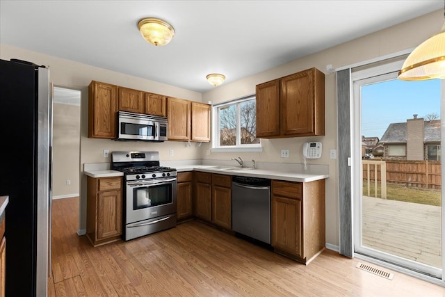 kitchen with stainless steel appliances, sink, and light hardwood / wood-style floors