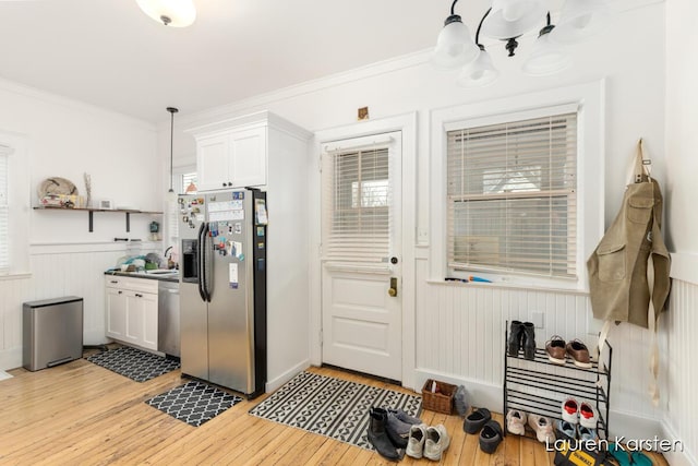 kitchen with appliances with stainless steel finishes, decorative light fixtures, light hardwood / wood-style flooring, and white cabinets