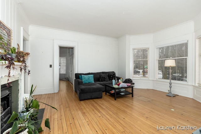 living room with crown molding, a high end fireplace, and light hardwood / wood-style flooring