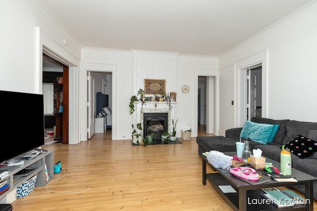 living room with ornamental molding, a premium fireplace, and light hardwood / wood-style flooring