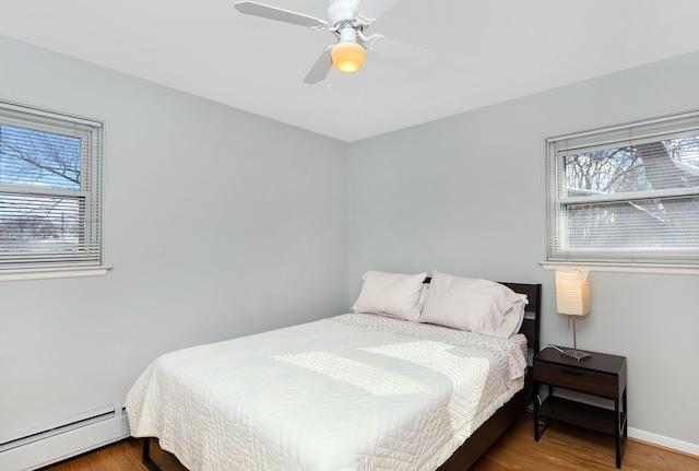 bedroom with a baseboard heating unit, wood-type flooring, and ceiling fan