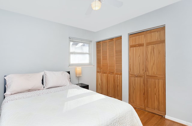 bedroom featuring two closets, ceiling fan, and light hardwood / wood-style flooring