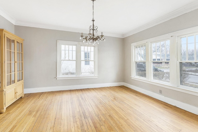 unfurnished dining area featuring crown molding, an inviting chandelier, and light wood-type flooring