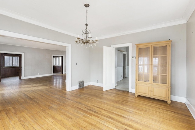 unfurnished room with crown molding, light hardwood / wood-style floors, and a chandelier