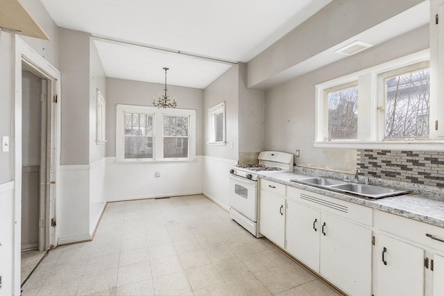 kitchen featuring pendant lighting, white cabinets, sink, and white range with gas stovetop