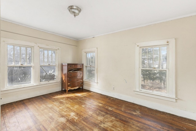 empty room featuring dark wood-type flooring and ornamental molding