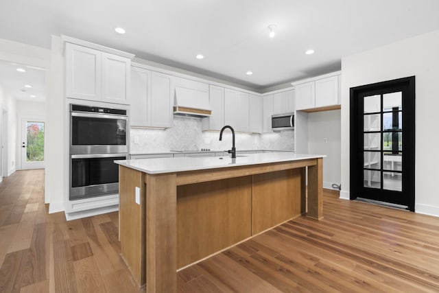 2735 Blue Bird Ln, Highland, MI 48357 - kitchen featuring stainless steel appliances, light wood finished floors, a sink, light countertops, and backsplash