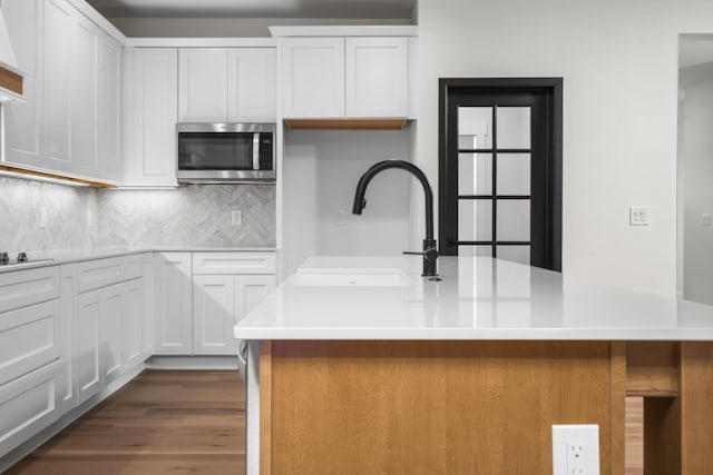 2735 Blue Bird Ln, Highland, MI 48357 - kitchen with stainless steel microwave, tasteful backsplash, and white cabinetry