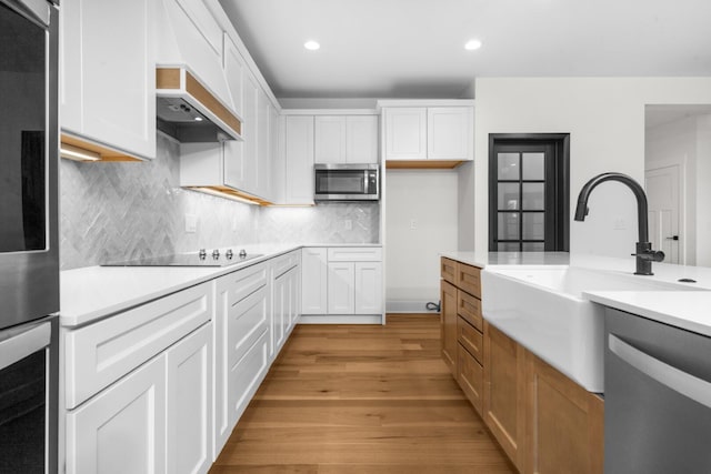 2735 Blue Bird Ln, Highland, MI 48357 - kitchen featuring stainless steel appliances, light wood finished floors, a sink, light countertops, and decorative backsplash