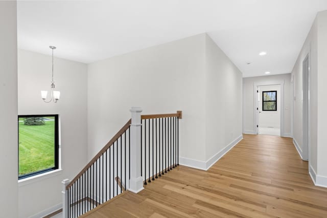 2735 Blue Bird Ln, Highland, MI 48357 - corridor featuring light wood-type flooring, an upstairs landing, a chandelier, baseboards, and recessed lighting