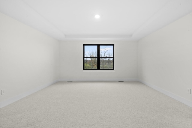 2735 Blue Bird Ln, Highland, MI 48357 - spare room with light colored carpet, a tray ceiling, and baseboards