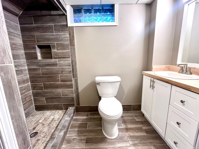 bathroom with vanity, toilet, and tiled shower