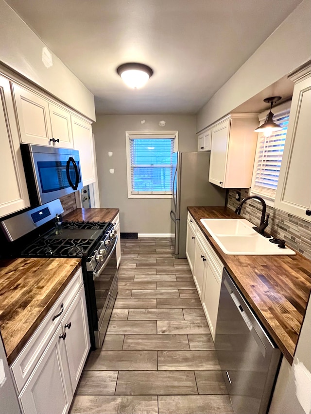 kitchen with stainless steel appliances, sink, butcher block countertops, and decorative backsplash