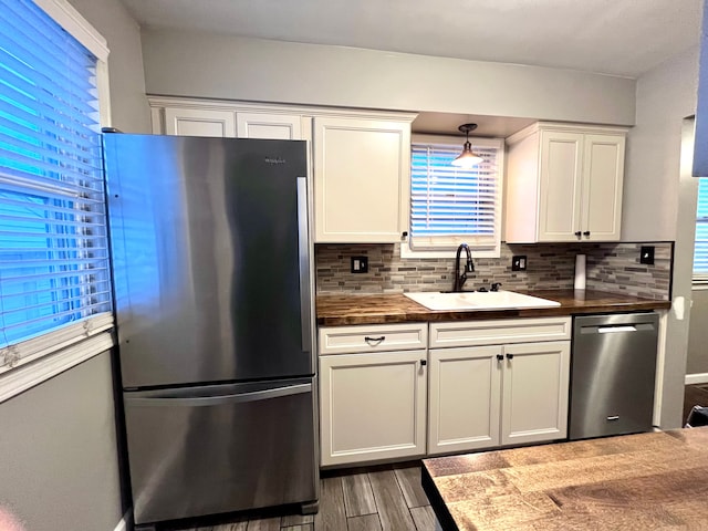 kitchen featuring decorative light fixtures, tasteful backsplash, sink, white cabinets, and stainless steel appliances