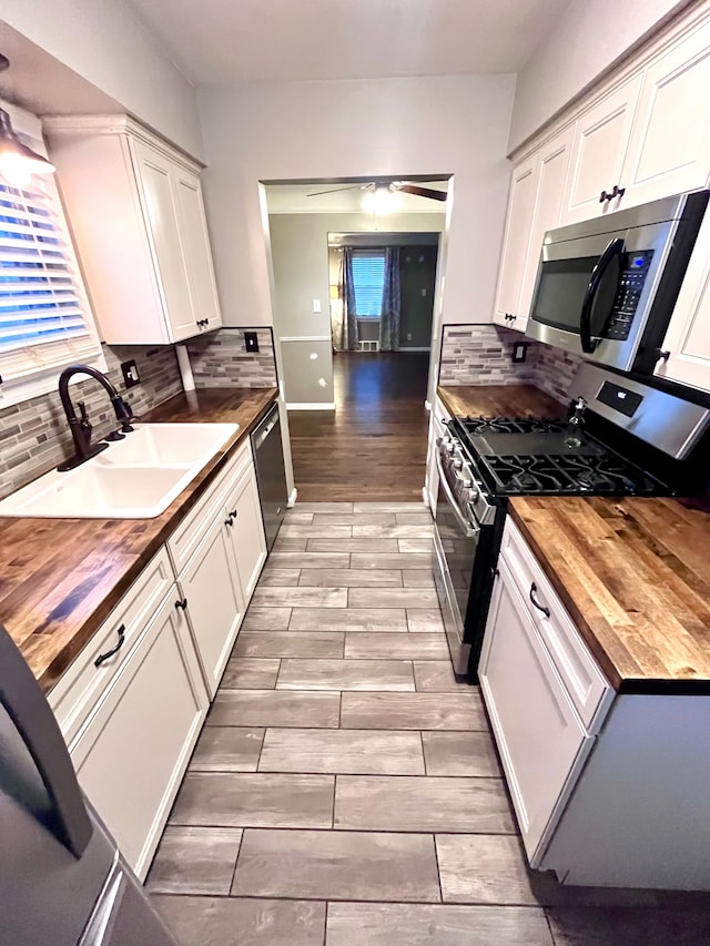 kitchen with white cabinetry, wooden counters, stainless steel appliances, and sink