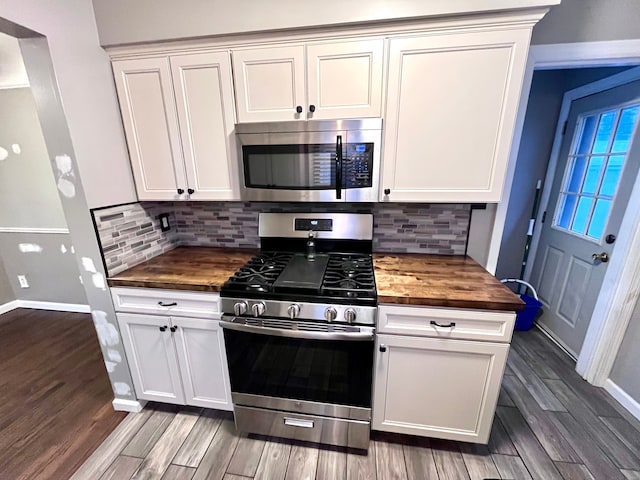 kitchen with stainless steel appliances, dark wood-type flooring, white cabinets, and wooden counters